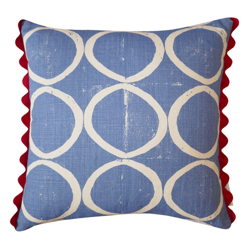 Circle print blue square cushion with red scalloped trim.