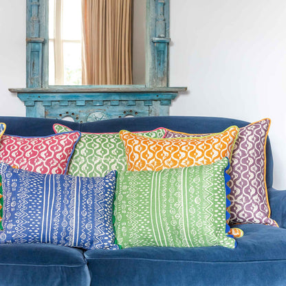 Geometric floral motif green square cushion with pink trim.