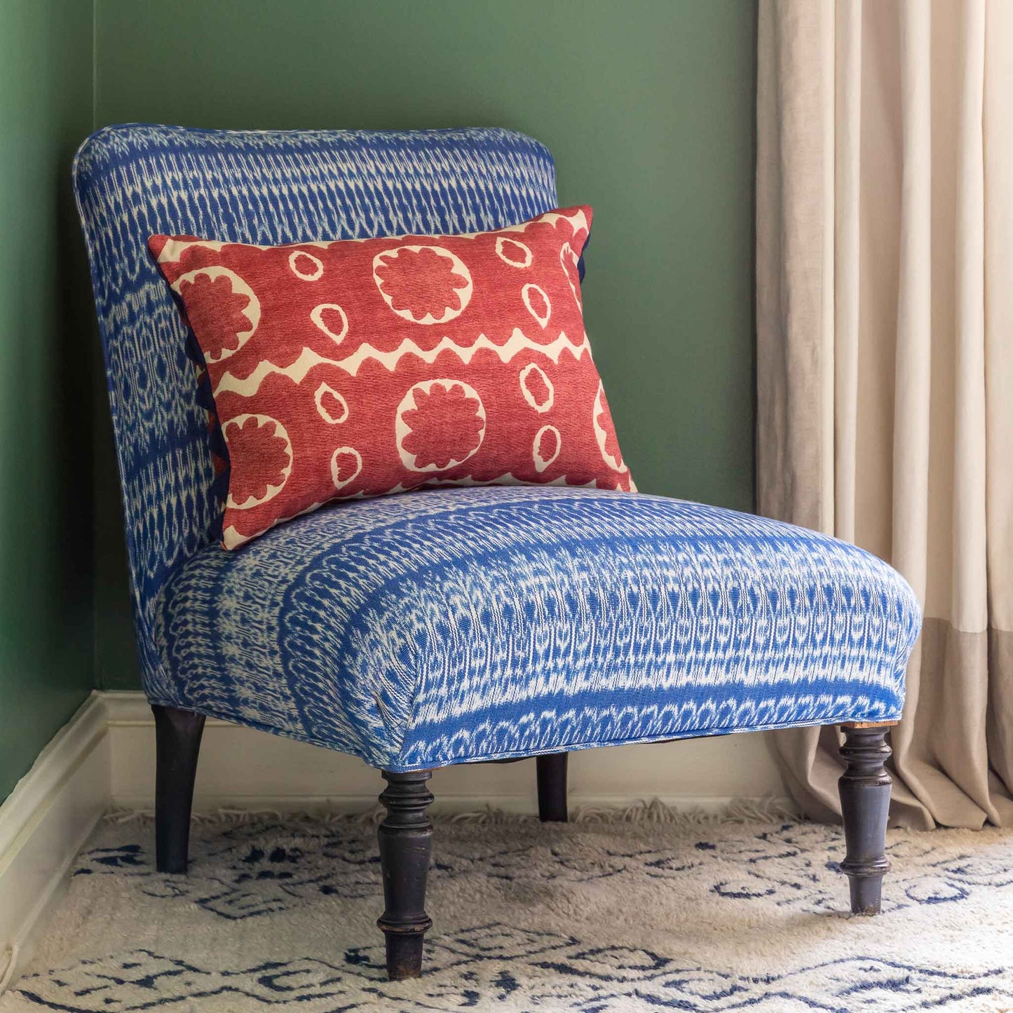 Red floral oblong cushion with navy blue scalloped trim. 